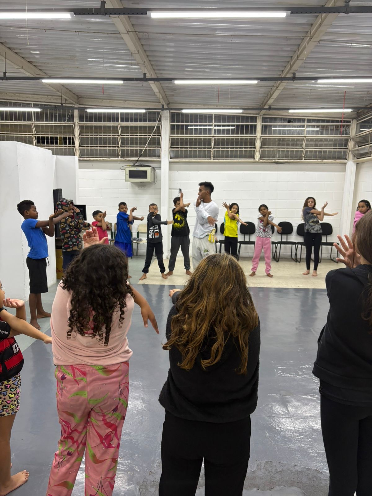 Participantes fazendo exercícios de alongamento durante a aula de Capoeira