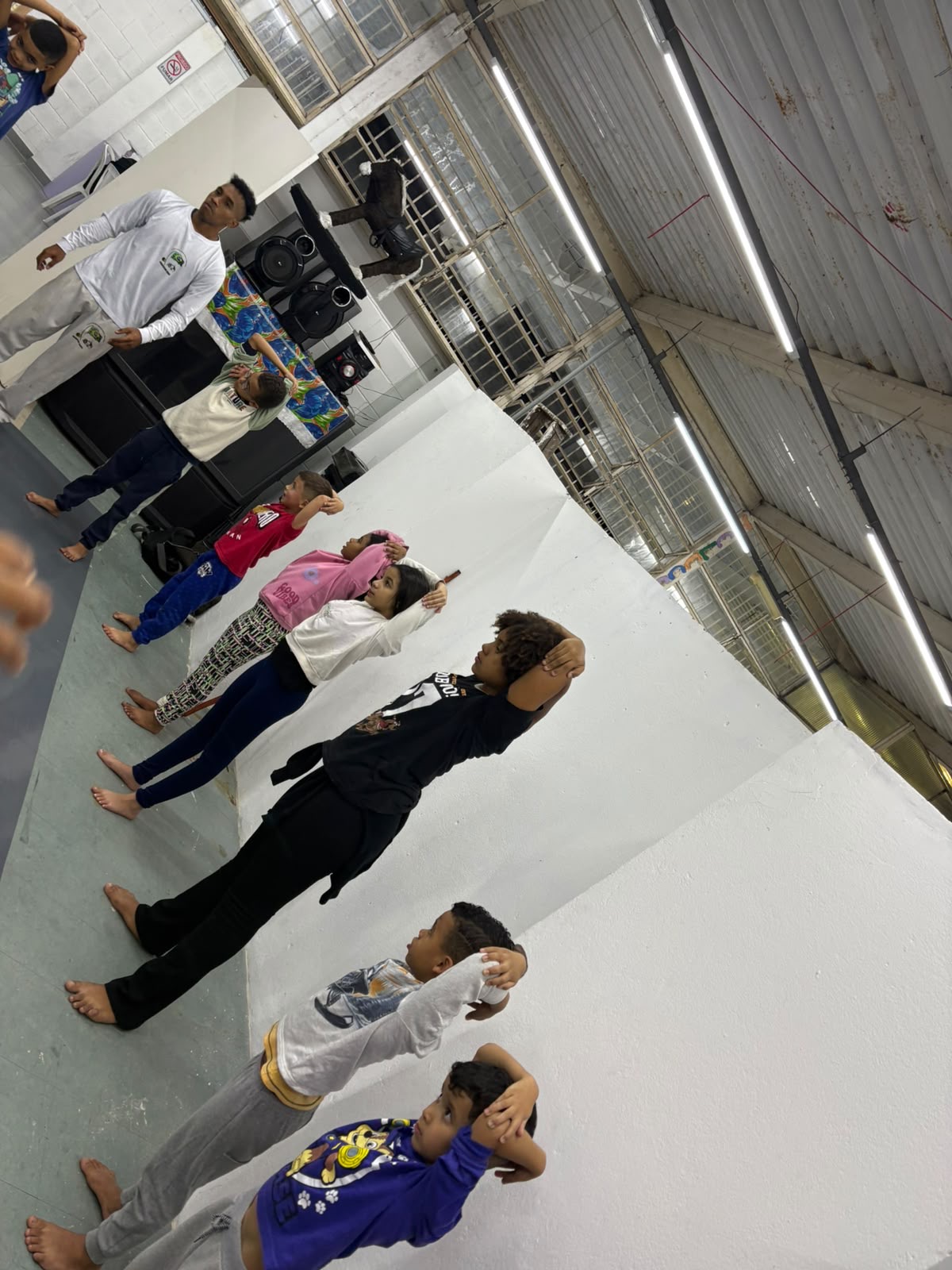 Crianças e adolescentes em fila realizando exercícios da aula de Capoeira